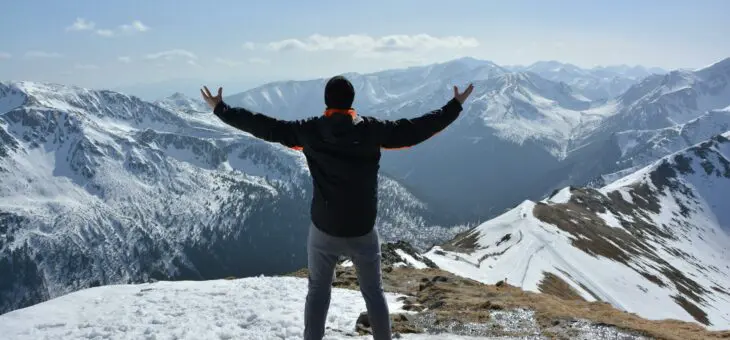 Hiker on top of a mountain celebrating with his arms outstretched