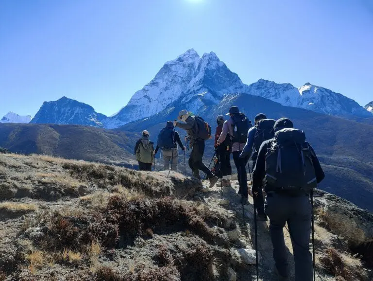 Trekkers on the way to Everest Base Camp, Nepal, picking their way over uneven terrain on a clear day.