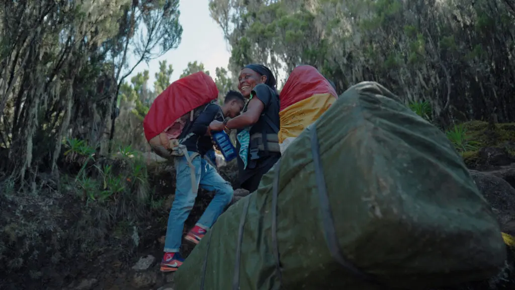 Porters carrying bags through the rainforest on Kilimanjaro