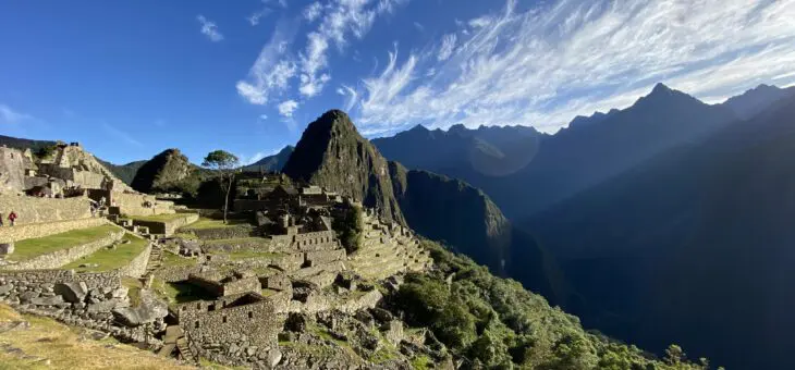 Machu Picchu site bathed in sunshine with some Inkan terraces visible and Huayna Picchu Mountain in the background