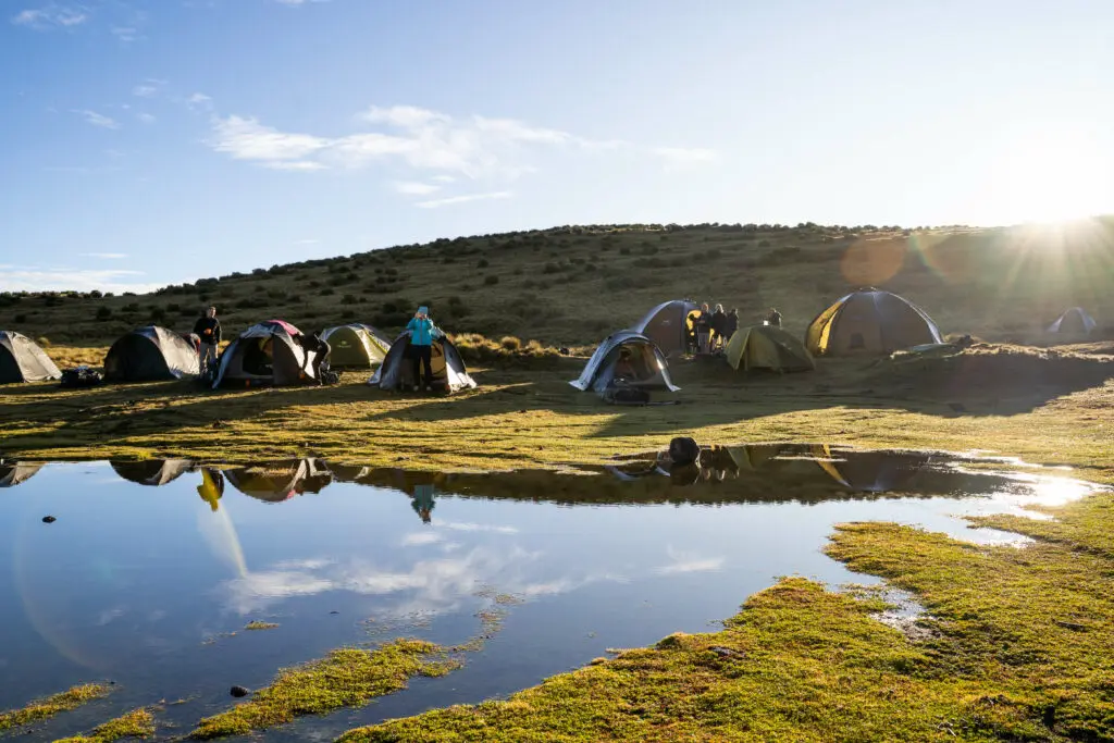 Tents bathed in sunshine set up along the lush lakefront on the Mt Kenya Tri Adventure