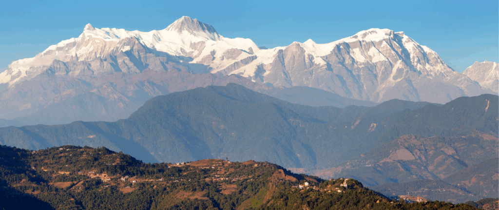 Panoramic views on the Annapurna Circuit in Nepal, with tall mountains visible in the background against a clear blue sky