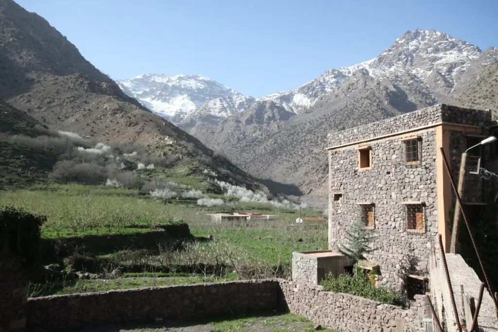 A tall stone building standing in front of a view of the High Atlas Mountains and snow-capped Mount Toubkal in Morocco