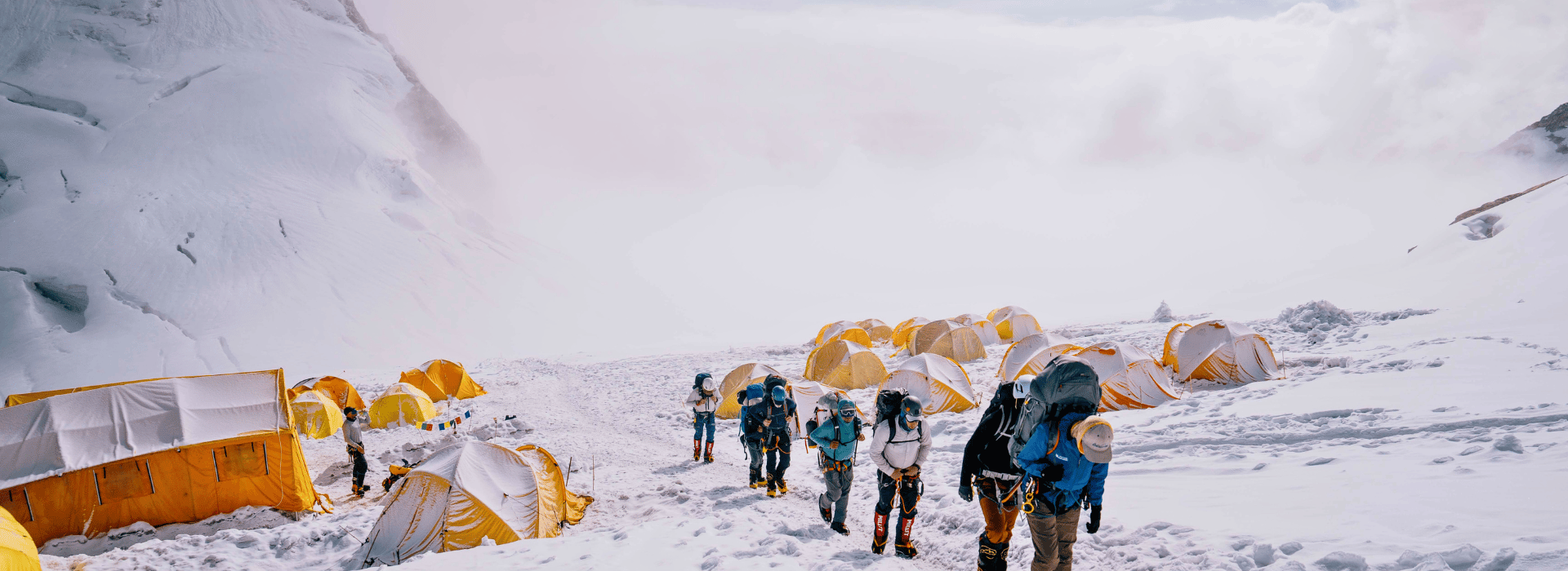 Climbers leaving camp with heavy packs on Manaslu