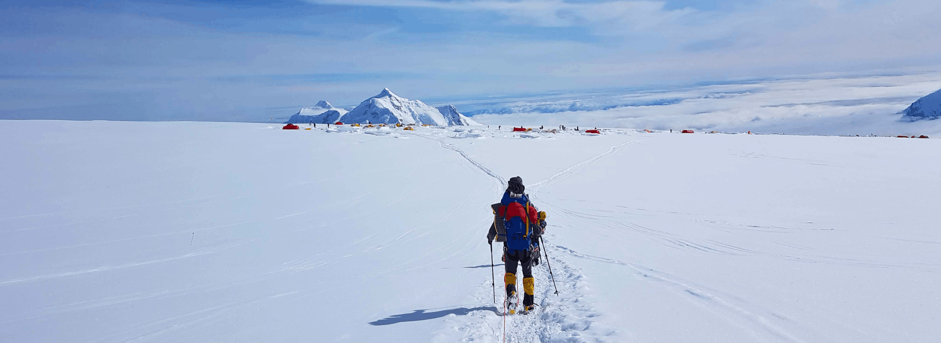 Climber returning to Basin Camp (C3) through snow with camp in the distance