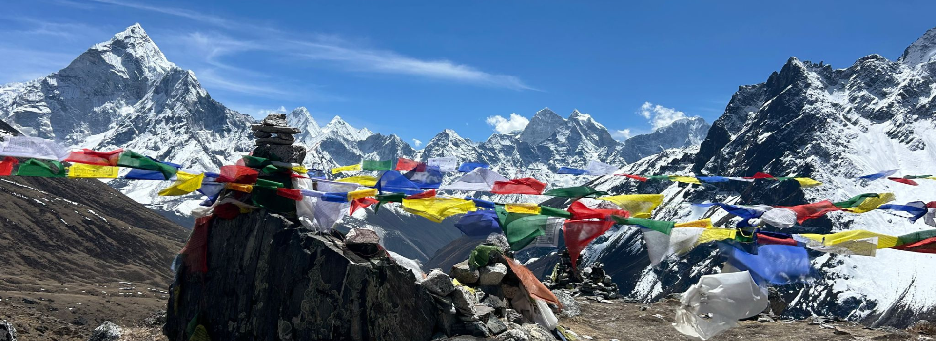Snow capped mountains against blue skies and prayer flags in foreground
