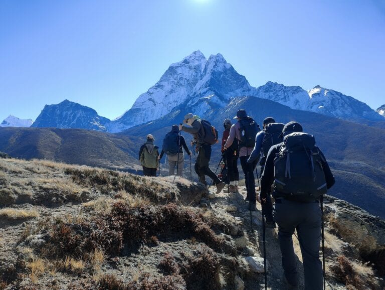Trekkers on the way to Everest Base Camp, Nepal, picking their way over uneven terrain on a clear day.