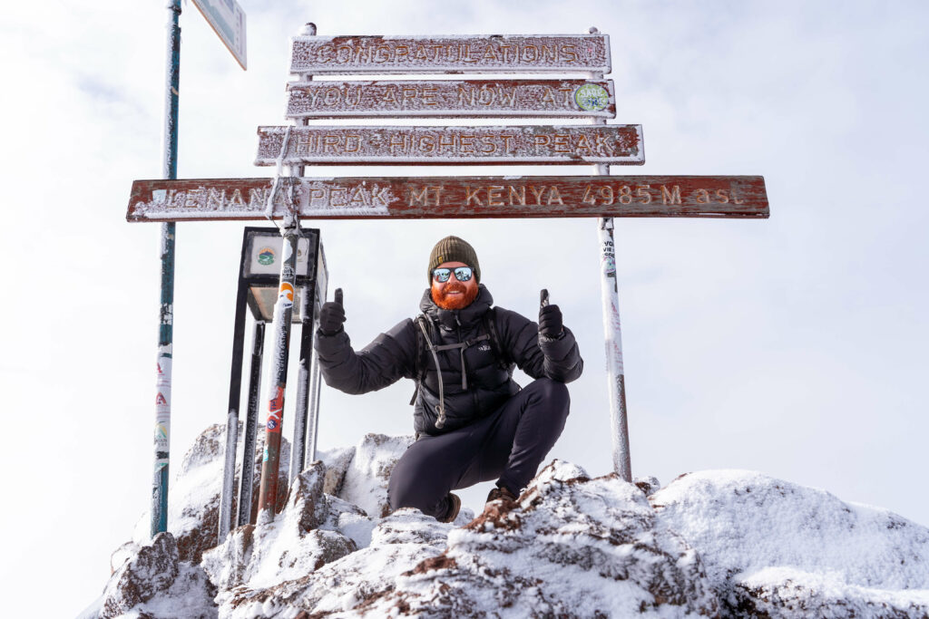 A climber who is happy after reaching the snowy summit of Mt. Kenya in daylight