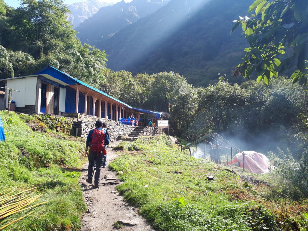 Trekkers in the lush Annapurna region approaching a local tea house for a rest, Nepal