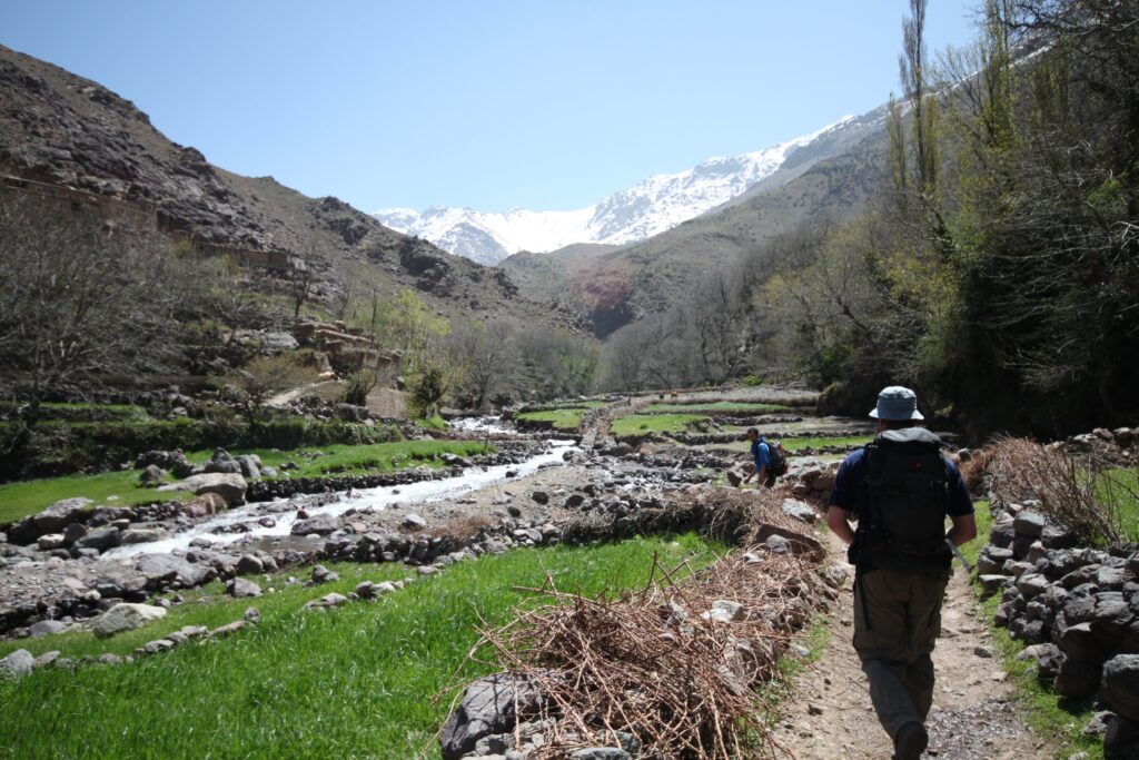 Trekkers hiking the Mount Toubkal Circuit, Morocco, with the snow-capped Mount Toubkal in the distance