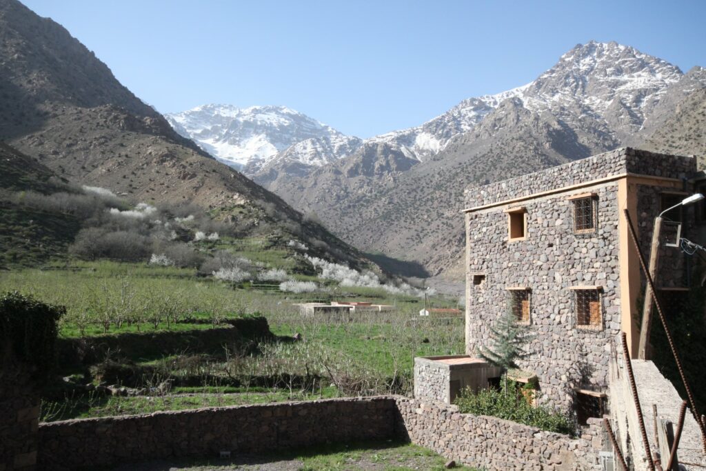 A tall stone building standing in front of a view of the High Atlas Mountains and snow-capped Mount Toubkal in Morocco