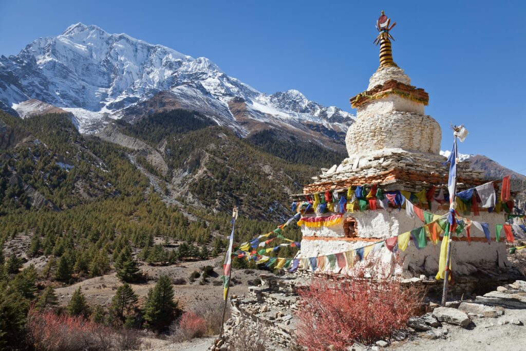 A Tibetan statue surrounded by prayer flags along a trail on the Annapurna Circuit, Nepal