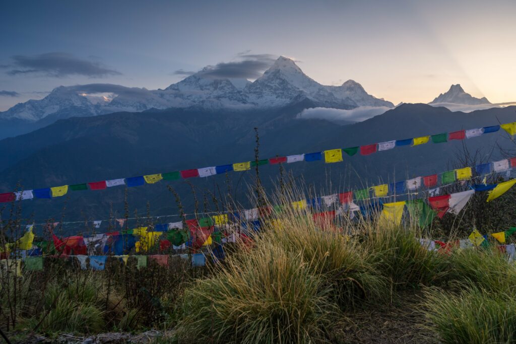 Prayer flags and the snow-covered peaks of the Annapurna massif at dusk, Nepal